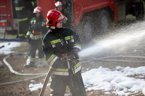 Firefighters extinguish a fire, with foam in the background